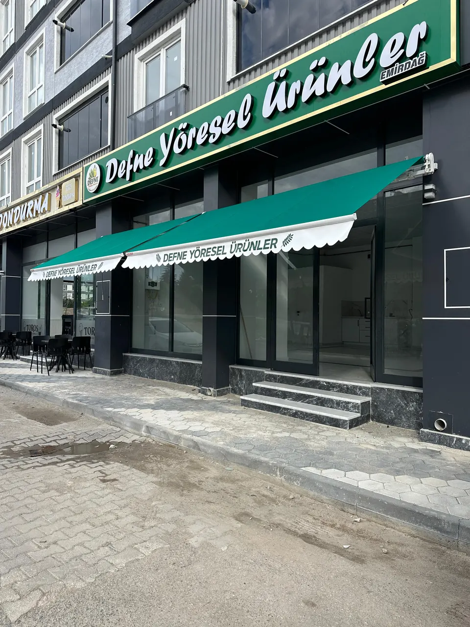 Emirdağ'da yeşil akrilik kumaşlı mafsallı tente ve beyaz dalgalı baskılı saçak