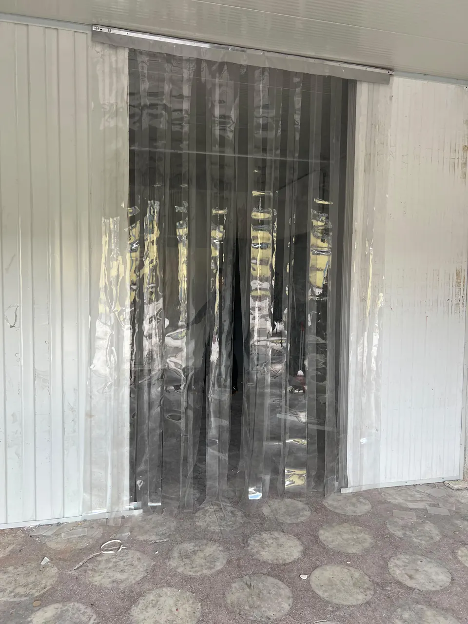 Geniş bir geçiş kapısını kapatan bindirmeli şeffaf PVC şerit perde