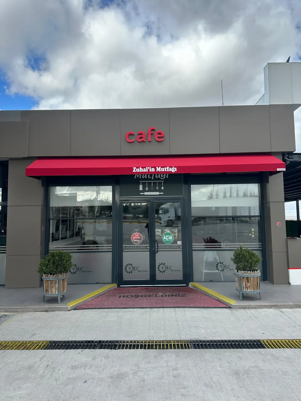 Modern kafe cephesinde vitrin boyunca uzanan kırmızı kasetli mafsallı tente