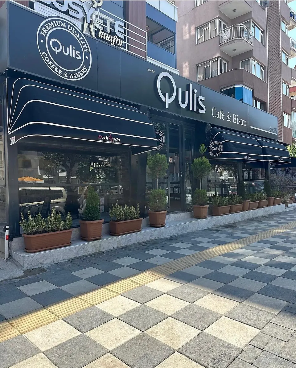 Kafe vitrinlerinin üzerine monte edilmiş beyaz şeritli siyah körüklü (kubbe) tenteler