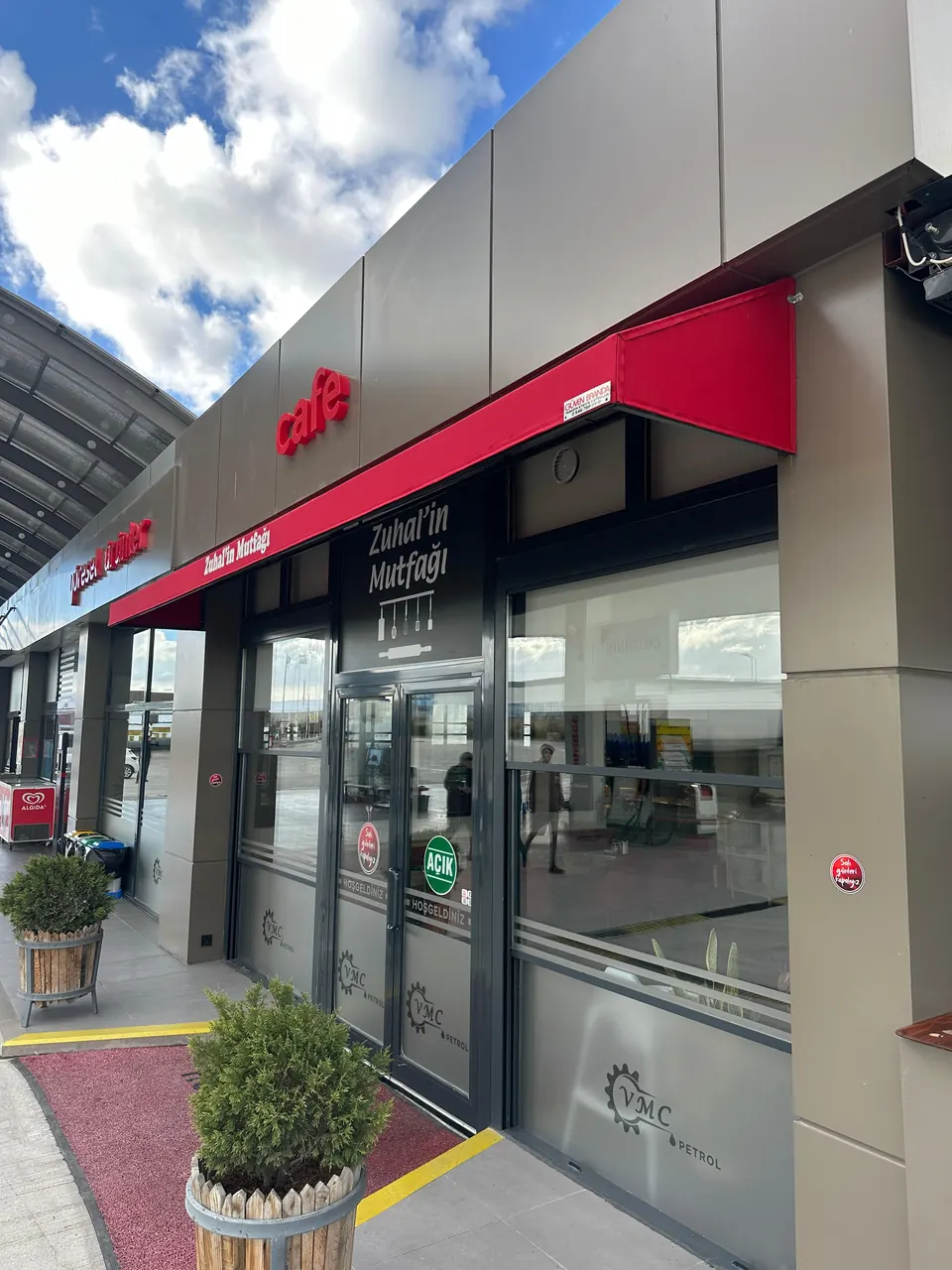 Kafe giriş kapısı üzerinde kırmızı mafsallı tente, yandan görünüm