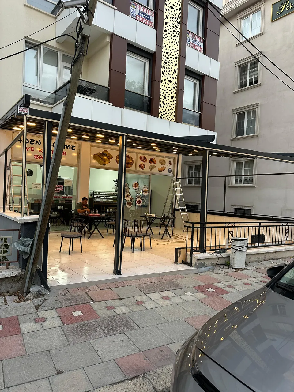 Apartman altındaki pastane terasını kapatan pergole tentenin dışarıdan görünümü