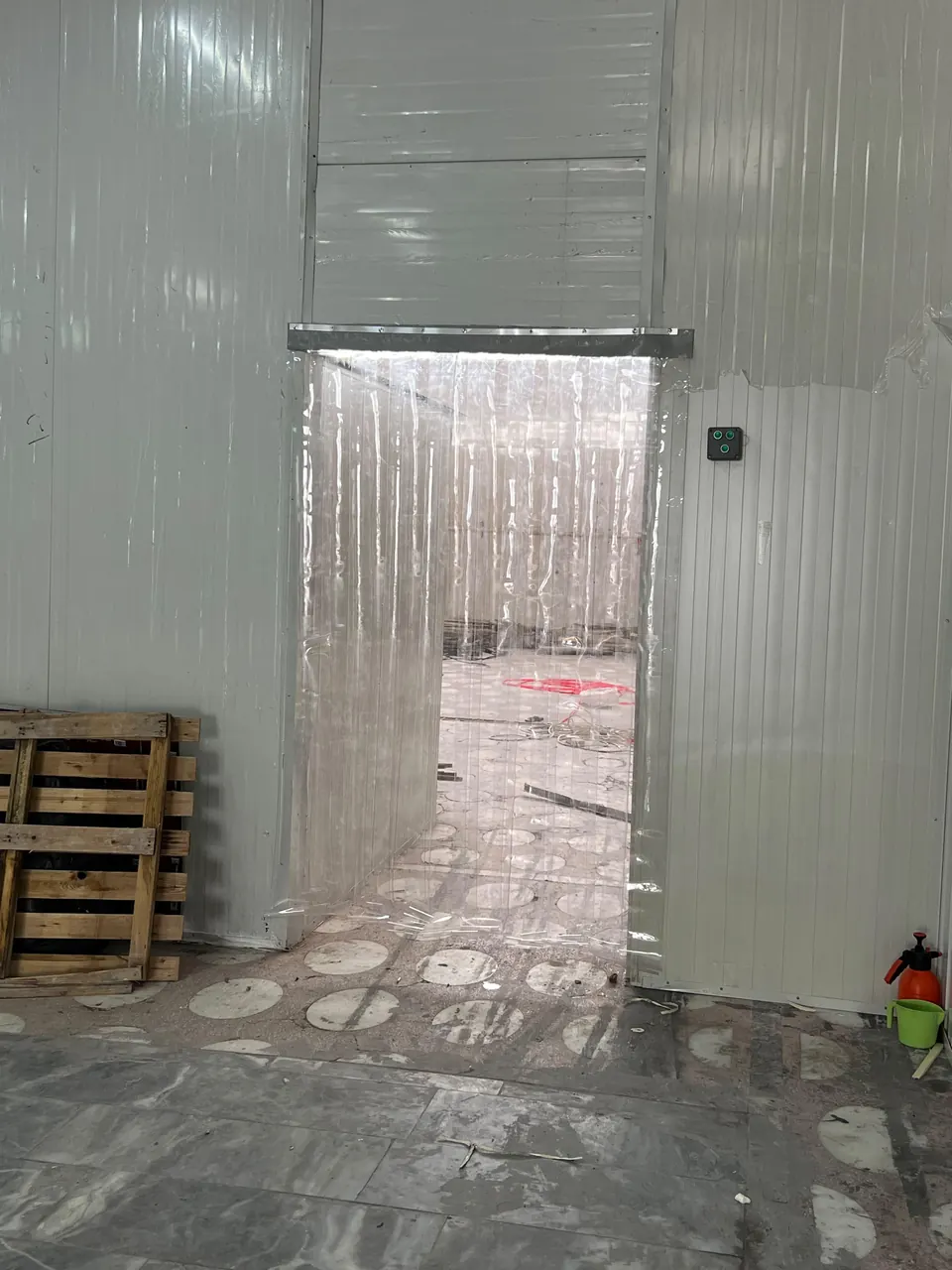 Panel duvarlı depo girişine paslanmaz askıyla monte edilmiş şeffaf PVC şerit perde
