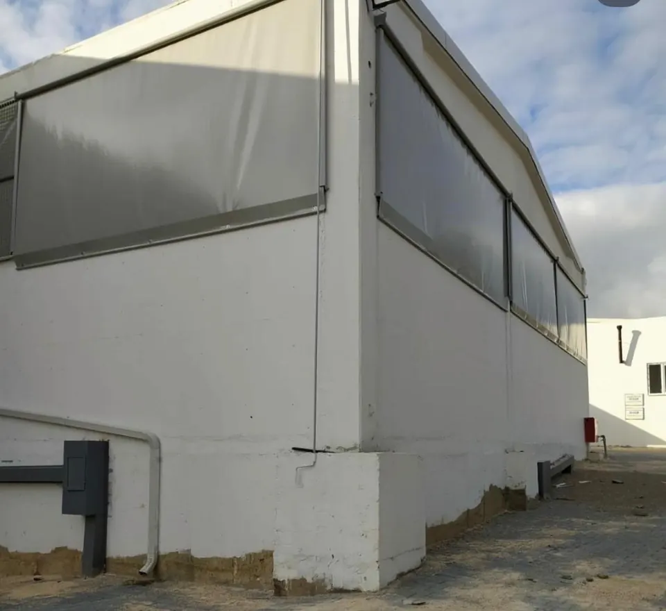 Endüstriyel bir yapının açık pencere bölümlerine takılan sarmal PVC branda rüzgâr perdeleri