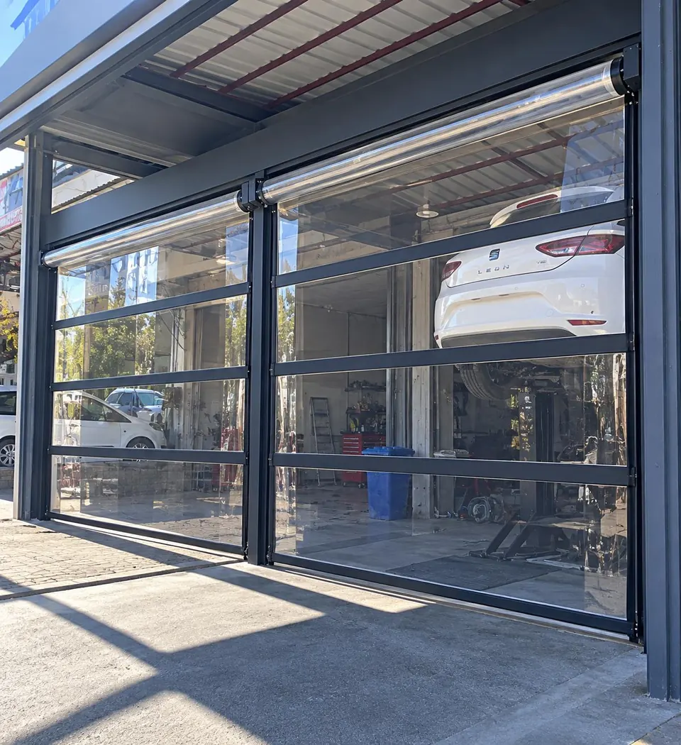Oto servis girişine monte edilen çift kanat şeffaf PVC sarmal branda kapı, siyah ara kuşaklı