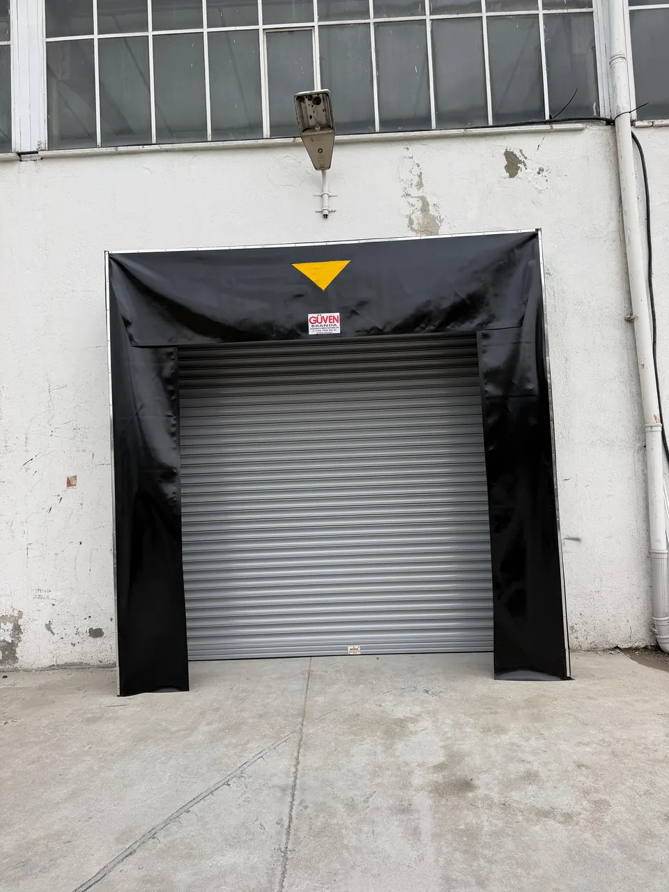 Fabrika yükleme kapısının çevresine monte edilen siyah PVC branda rampa körüğü